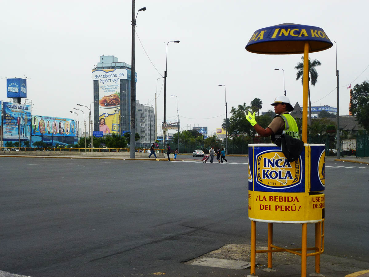 Transit officer directing traffic from a raised platform at an intersection in Lima.