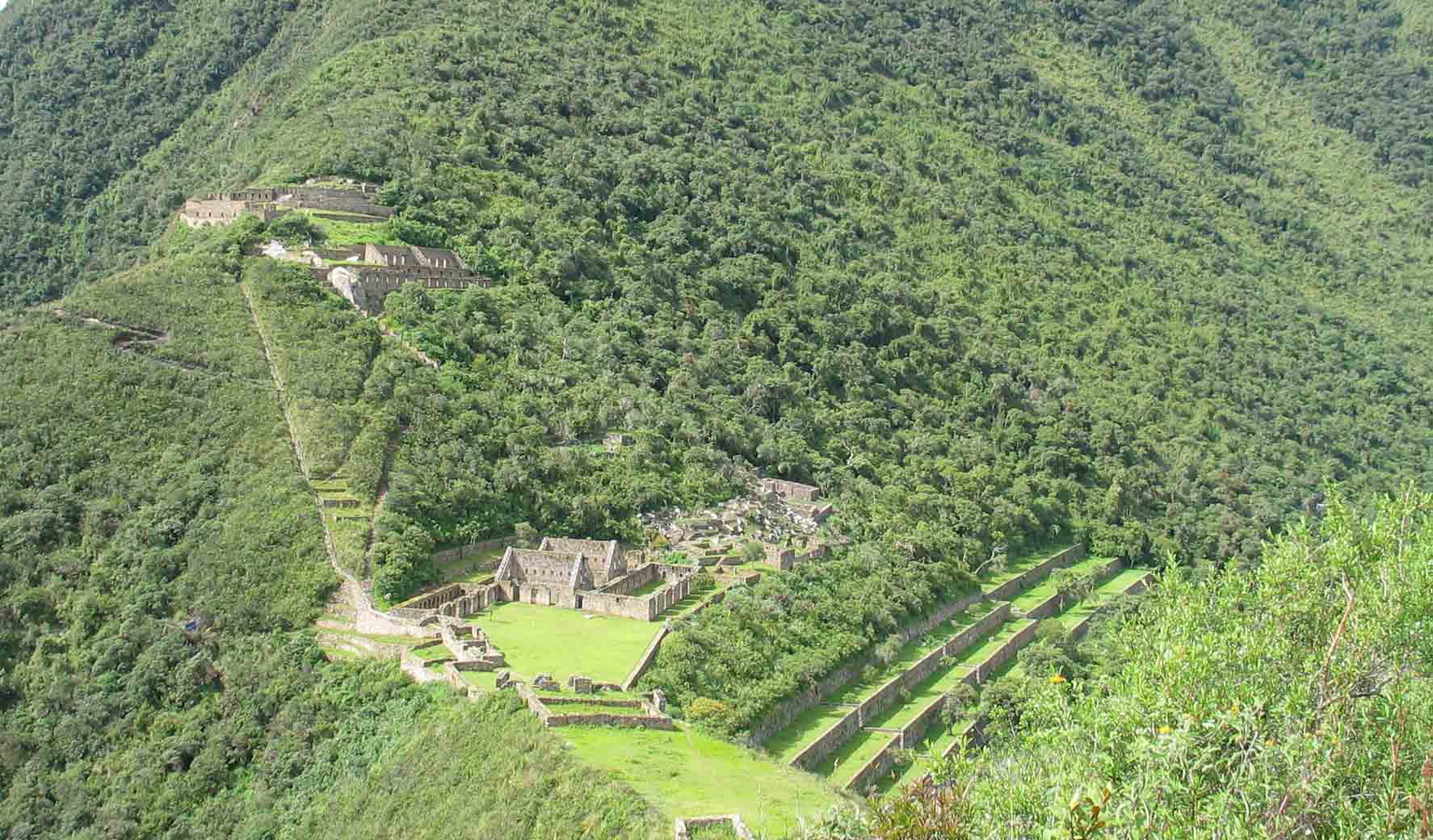 Several levels of stone ruins known as Choquequirao with surrounding greenery on a mountainside.