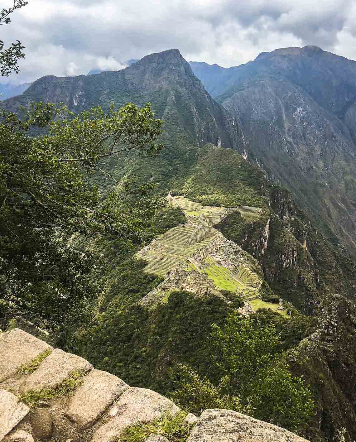 The tall mountain of Machu Picchu as seen from the Huayna Picchu summit on a cloudy day.